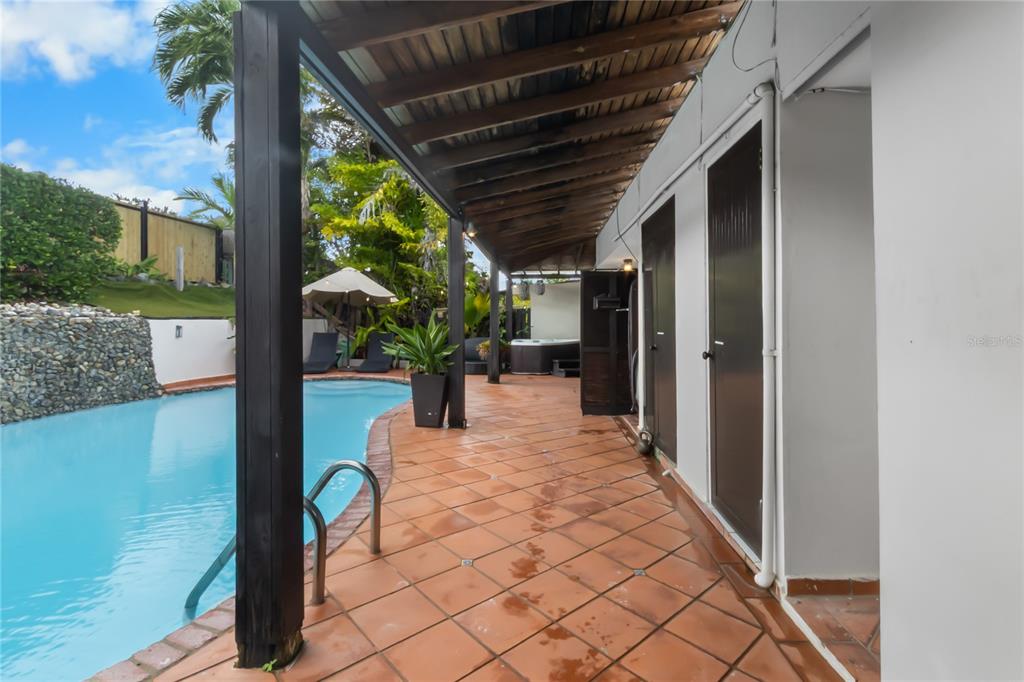 A covered patio with terracotta tile flooring overlooks a swimming pool and a hot tub — AD5 CALLE BALEARES, HUMACAO, PR