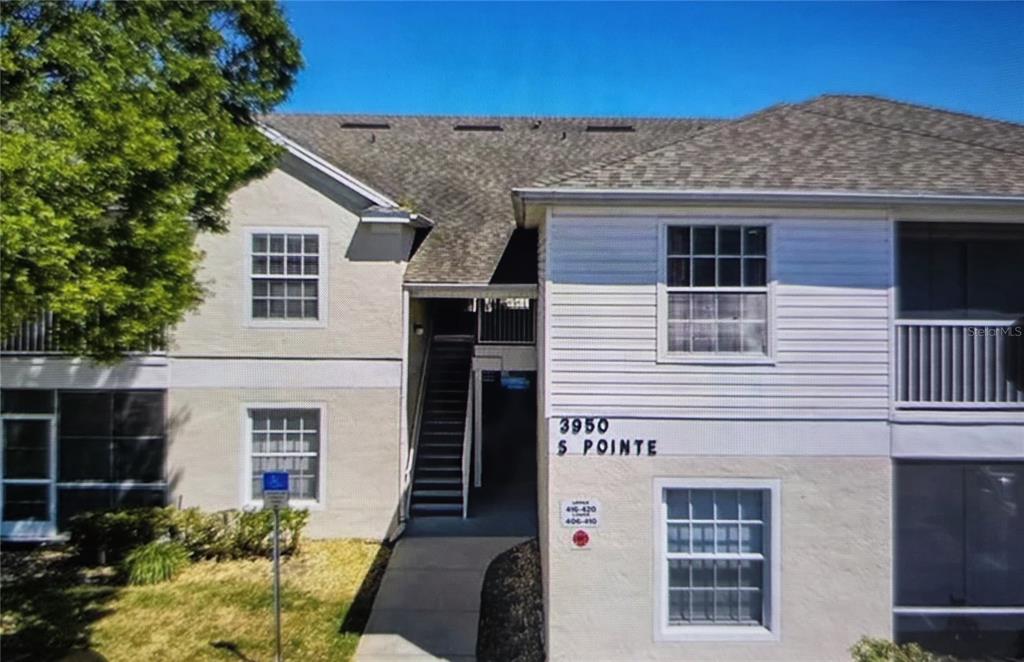 A two-story apartment building exterior features a central staircase, tan siding, and white trim — 3950 SOUTHPOINTE DRIVE UNIT 418, ORLANDO, FL