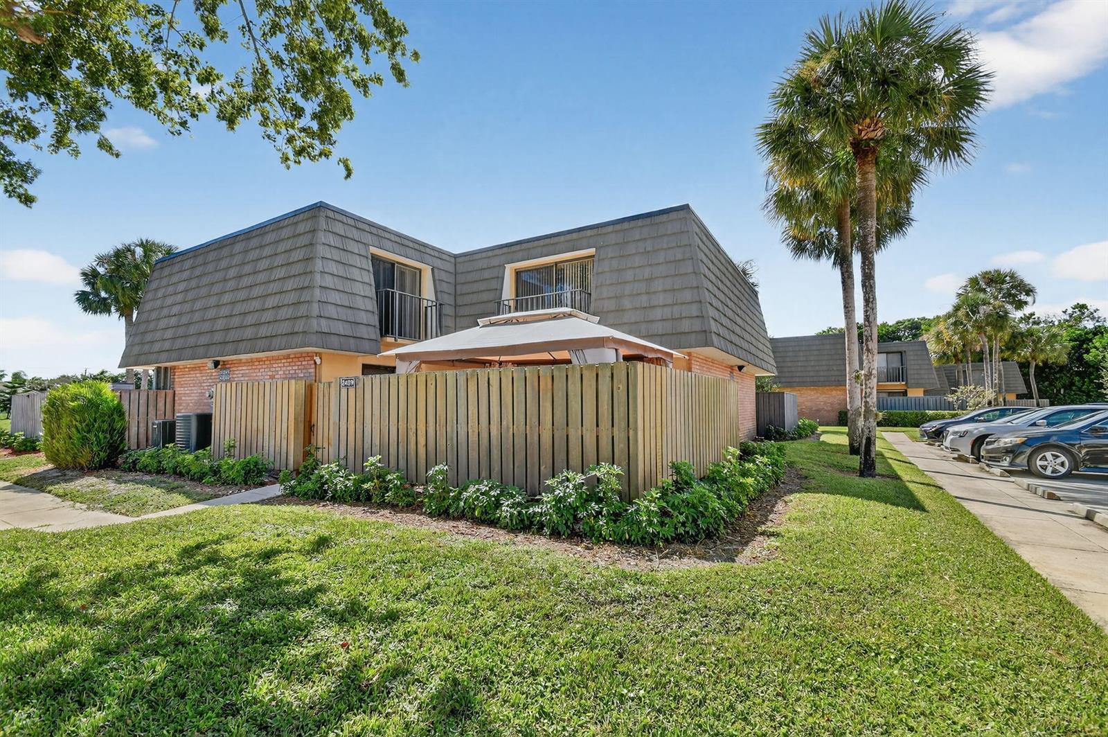 A concrete patio sits in front of a yellow house with a balcony and gazebo — 2409 24th Way, West Palm Beach FL 33407, WEST PALM BEACH, FL