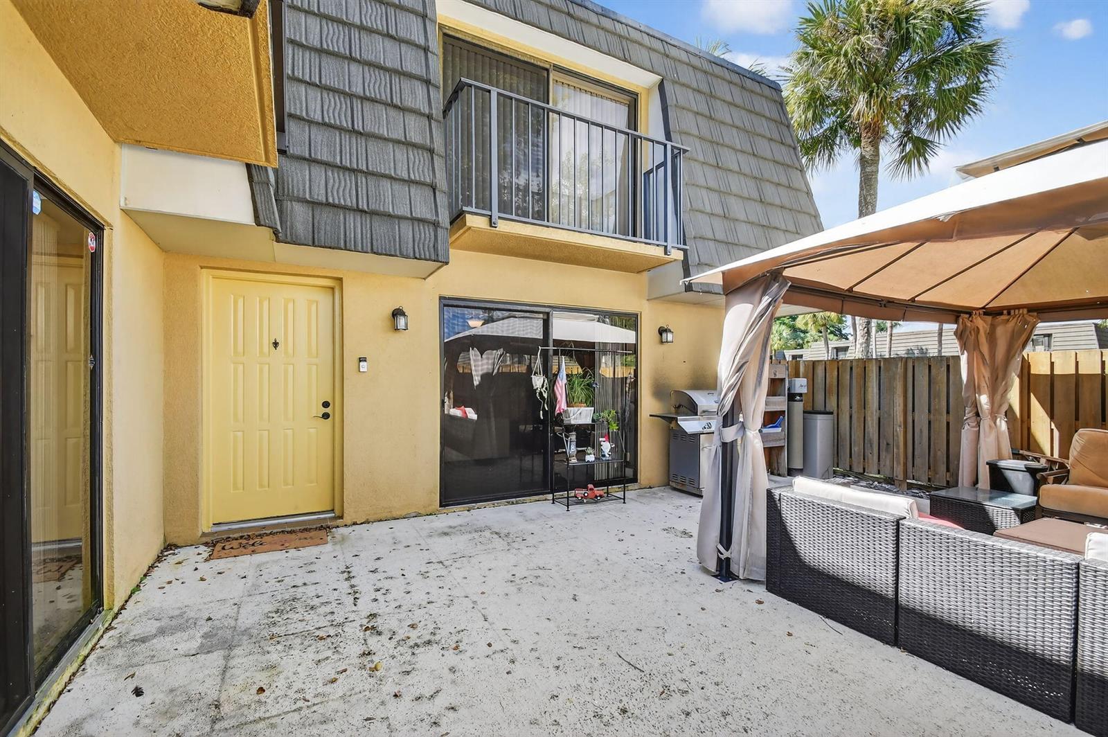 A beige gazebo stands on a concrete patio next to a two-story yellow house — 2409 24th Way, West Palm Beach FL 33407, WEST PALM BEACH, FL