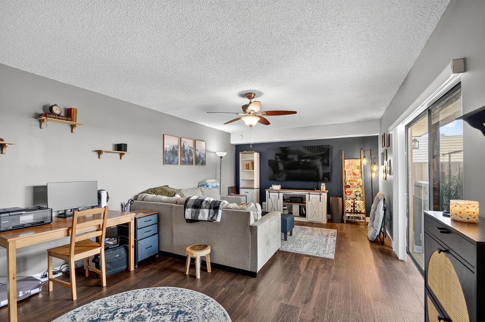 An empty living room with dark wood floors, a navy accent wall, and sliding glass doors — 2409 24th Way, West Palm Beach FL 33407, WEST PALM BEACH, FL
