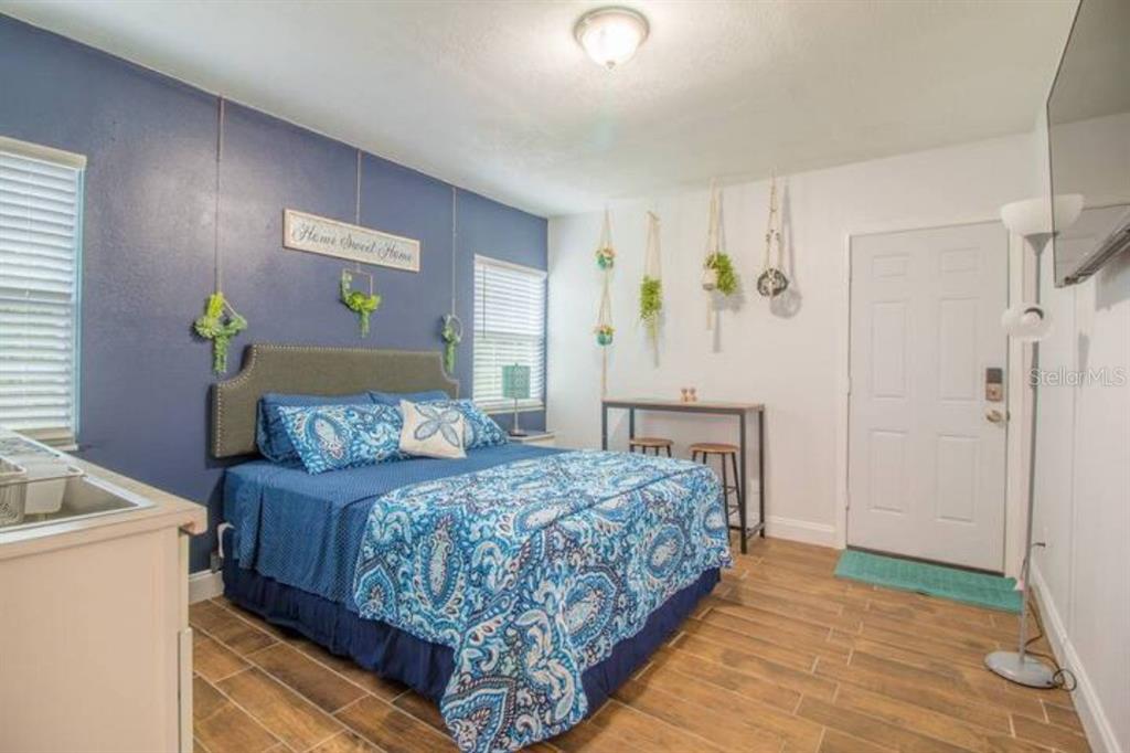 A bedroom with a blue accent wall, a patterned bedspread, and a small dining table — 2014 NEWMAN ST UNIT 3, ORLANDO, FL