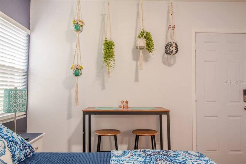 A bedroom features a small table with two stools, hanging macrame planters, and a patterned bedspread — 2014 NEWMAN ST UNIT 3, ORLANDO, FL
