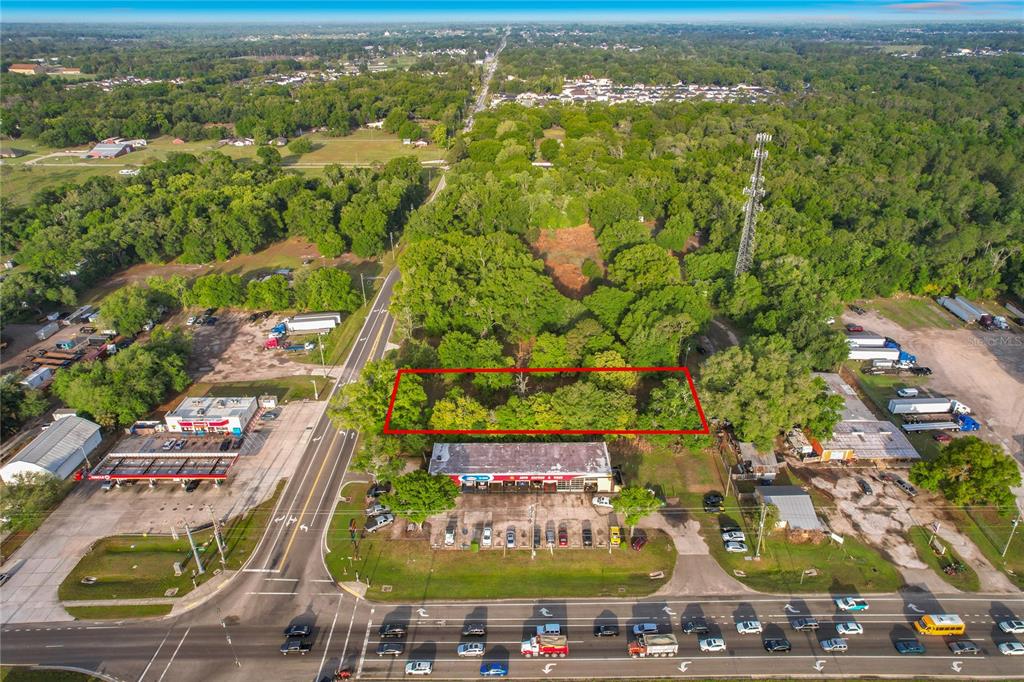 An aerial view shows a rectangular plot of land outlined in red behind a commercial building — 1215 DUFF ROAD, LAKELAND, FL