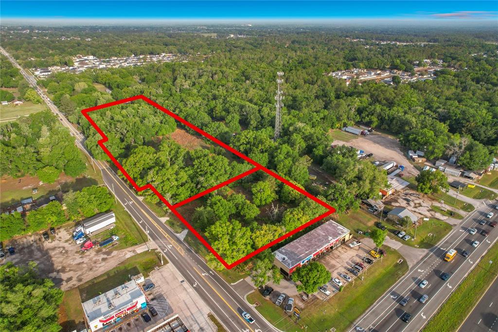 An aerial view shows a rectangular, wooded plot of land outlined in red near roads — 1215 DUFF ROAD, LAKELAND, FL
