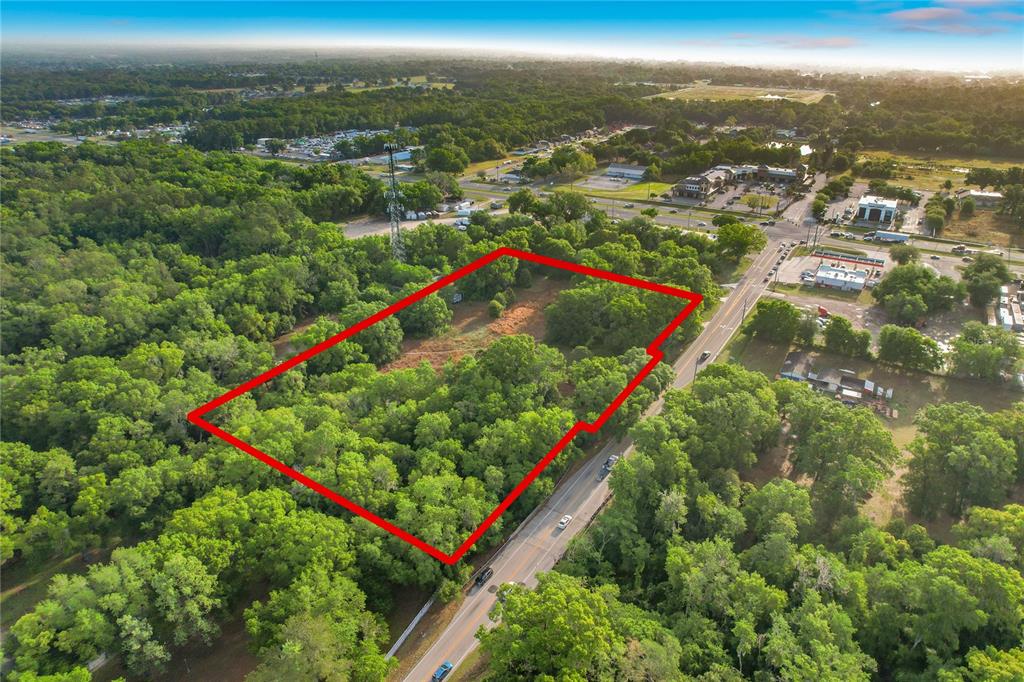 An aerial view shows a rectangular, wooded plot of land outlined in red beside a road — 1215 DUFF ROAD, LAKELAND, FL