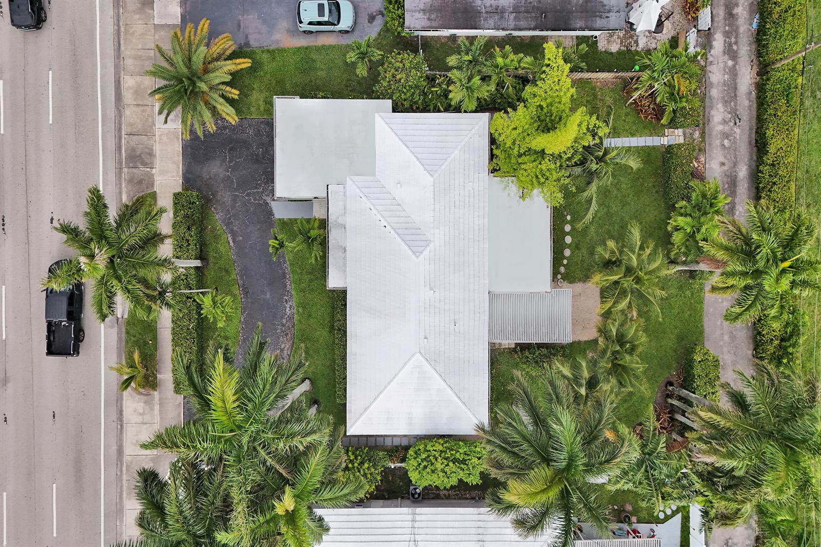 An aerial view shows a house with a white metal roof surrounded by palm trees — 3113 Hollywood Boulevard, Hollywood FL 33021, HOLLYWOOD, FL