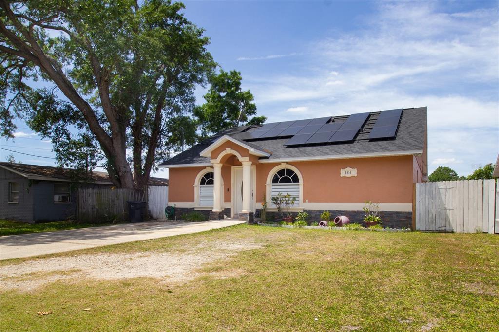 A single-story house with a tan stucco exterior, solar panels, and a paved driveway — 6914 N HIMES AVENUE, TAMPA, FL
