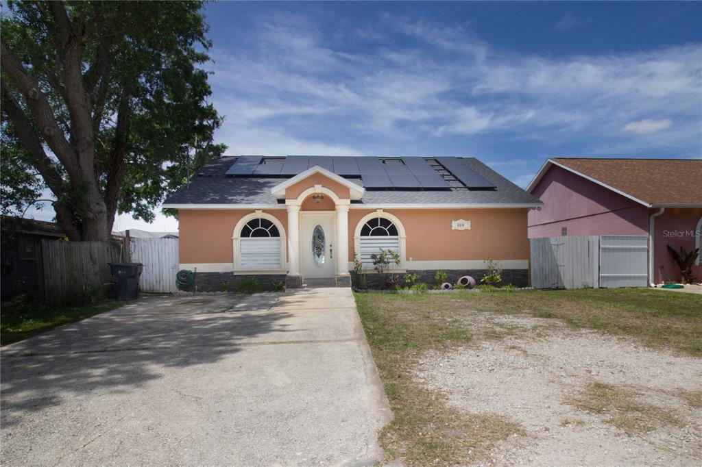 A single-story peach-colored house with a concrete driveway and solar panels on the roof — 6914 N HIMES AVENUE, TAMPA, FL
