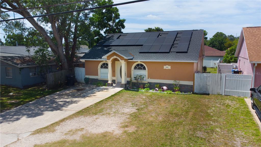 A single-story house with a solar panel array on the roof and a concrete driveway — 6914 N HIMES AVENUE, TAMPA, FL