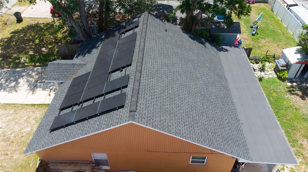 An aerial view of a house roof featuring solar panels and a flat roof section — 6914 N HIMES AVENUE, TAMPA, FL
