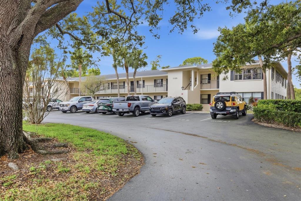 A two-story apartment building with a parking lot and several vehicles in front — 7130 FAIRWAY BEND LANE UNIT 291, SARASOTA, FL