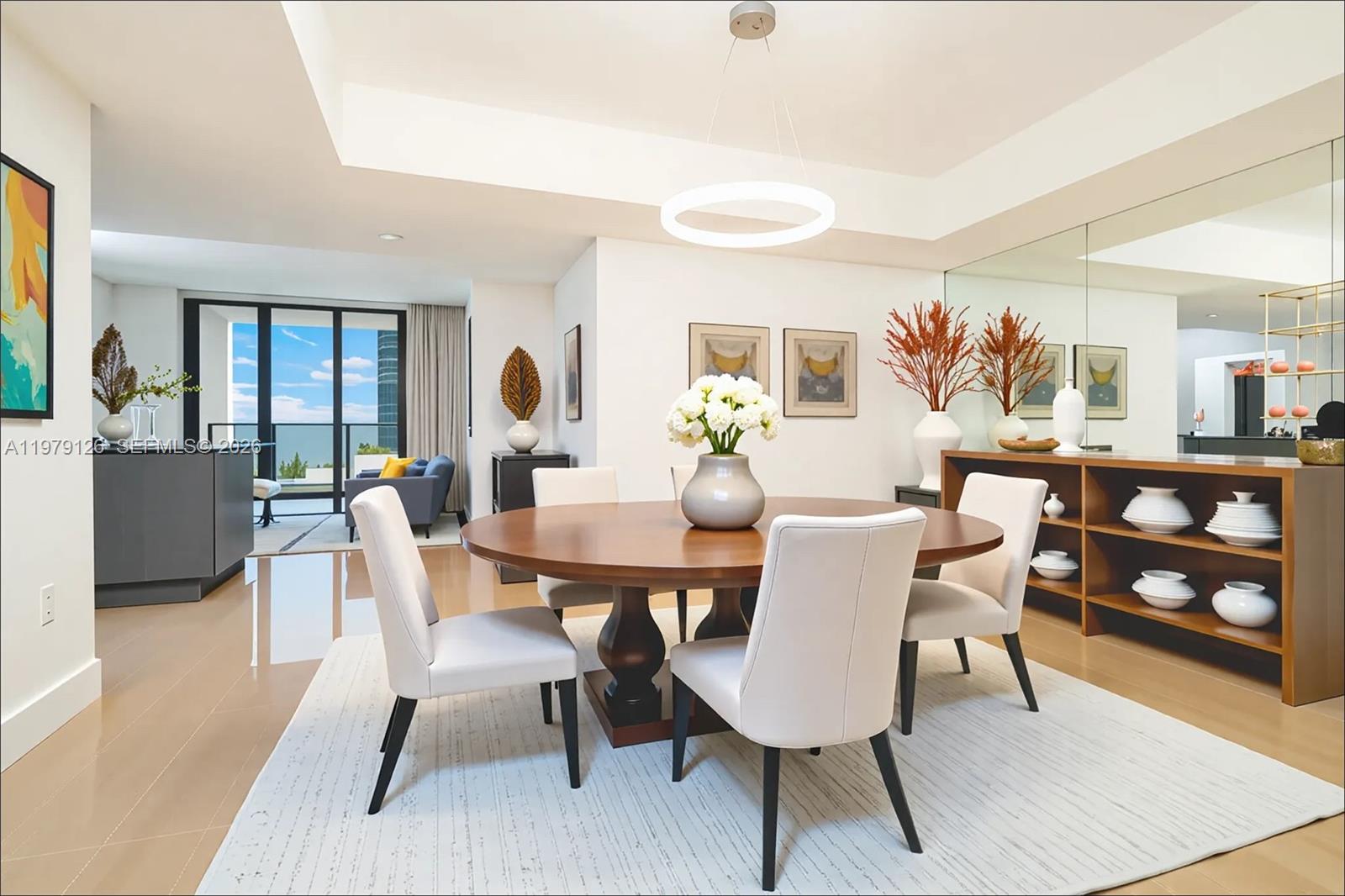 A dining room features a round wooden table, white chairs, and a modern circular chandelier — 1010 Brickell Ave # 1902, Miami FL 33131, MIAMI, FL