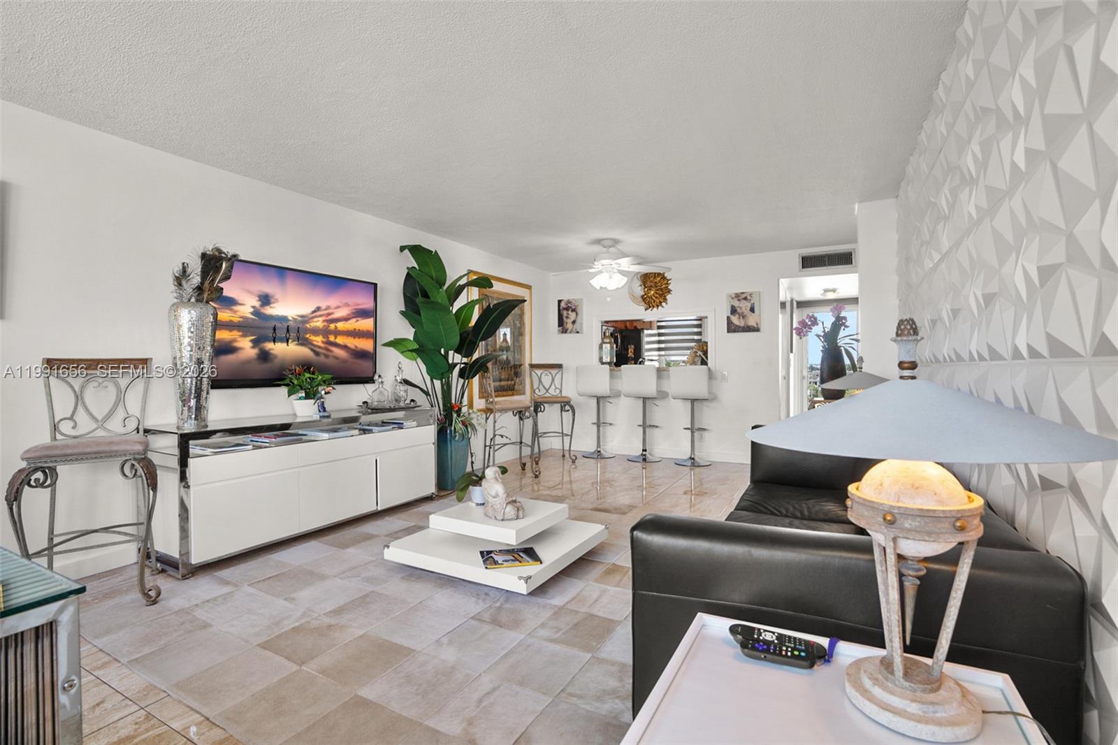 A living room features a white media console, a black sofa, and a textured wall — 201 N Ocean Blvd # 509, Pompano Beach FL 33062, POMPANO BEACH, FL