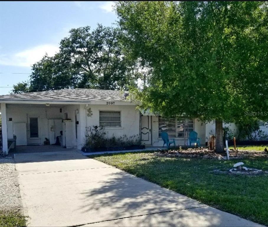 A single-story white house with a carport, a concrete driveway, and a large front tree — 2007 ELK AVENUE, SARASOTA, FL