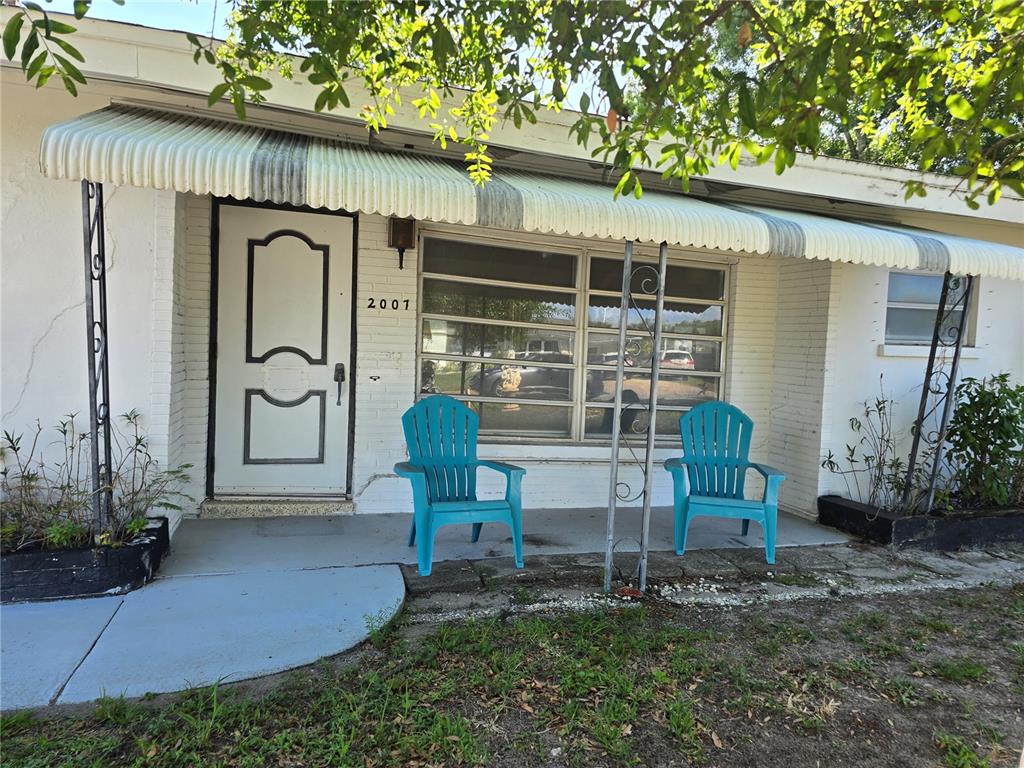 A white house exterior features a front porch with two blue chairs and metal awnings — 2007 ELK AVENUE, SARASOTA, FL