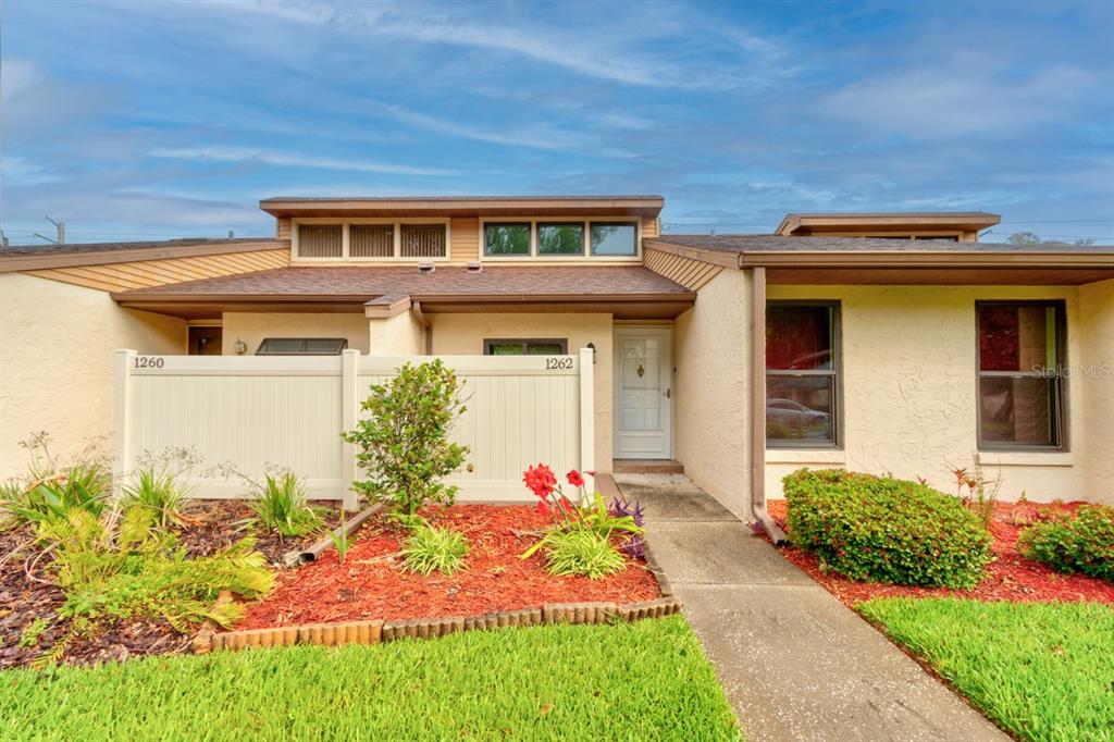 The exterior of a single-story residential building features a white fence and red mulch — 1262 CHARTER OAKS CIRCLE UNIT none, HOLLY HILL, FL