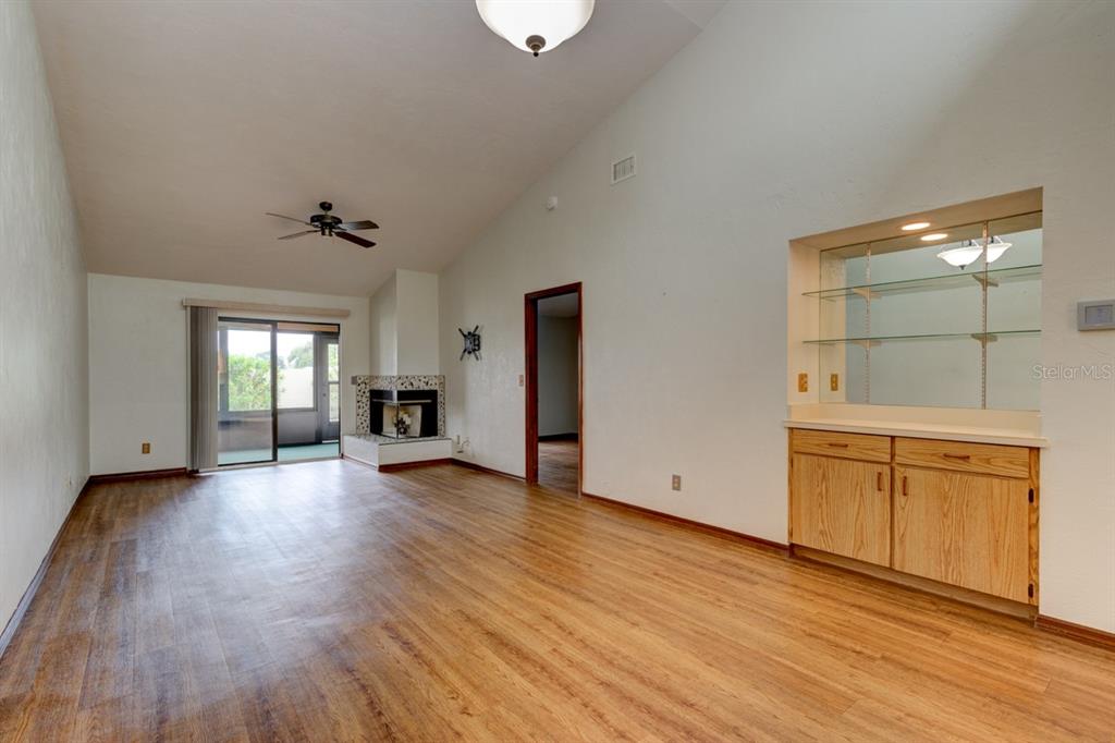 A living room with wood-look flooring, a fireplace, a wet bar, and sliding glass doors — 1262 CHARTER OAKS CIRCLE UNIT none, HOLLY HILL, FL