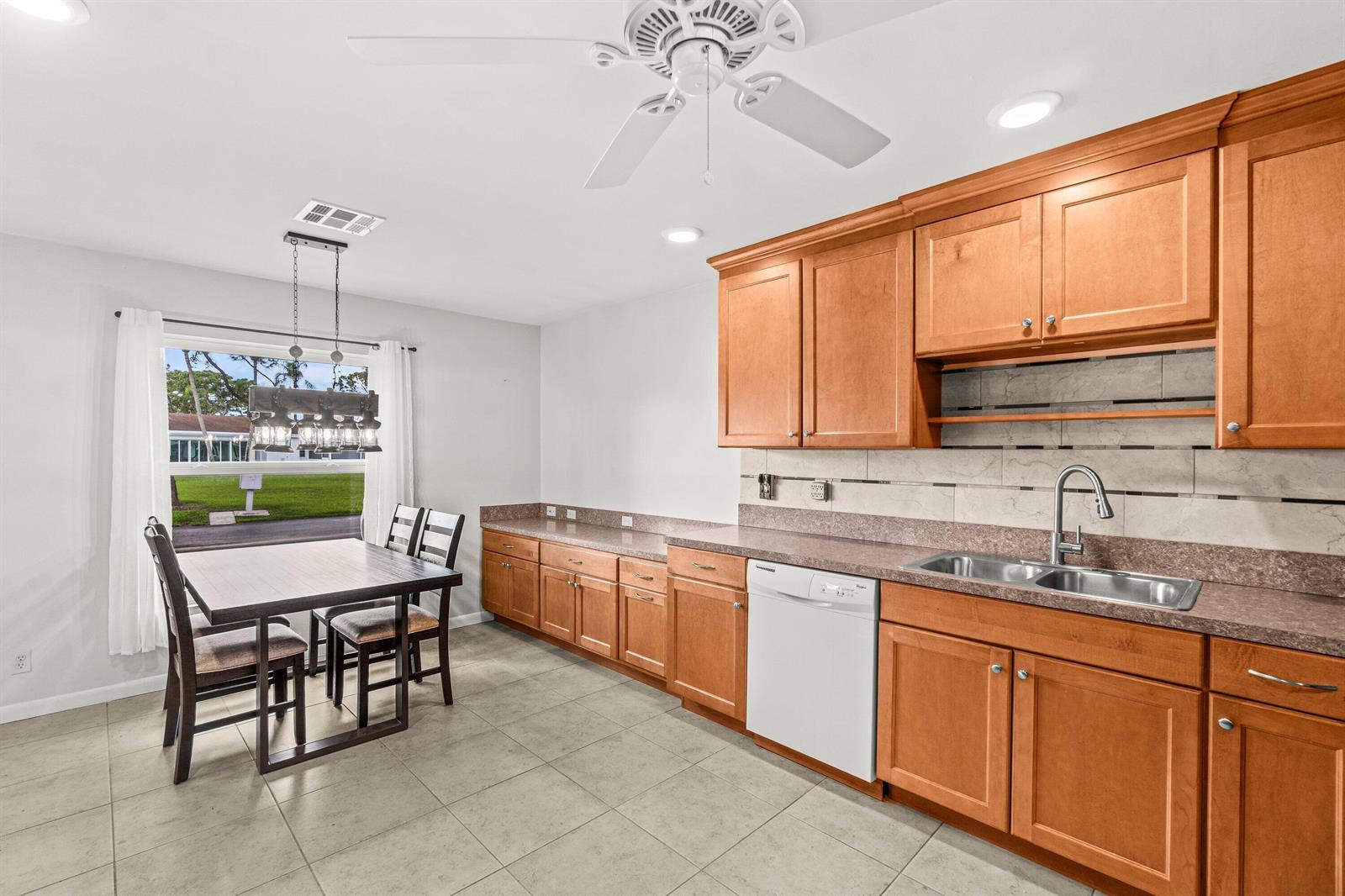 A kitchen with wood cabinets, a dining table, and a window overlooking a grassy lawn — 5074 Privet Place # B, Delray Beach FL 33484, DELRAY BEACH, FL