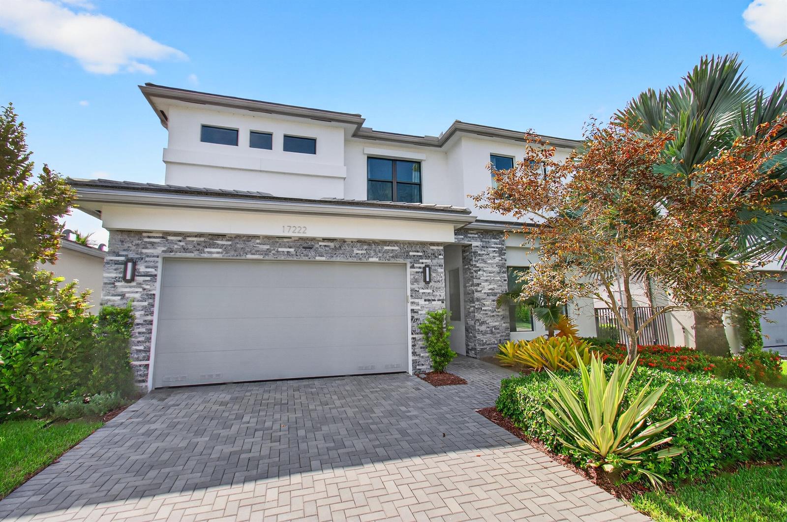 A two-story house features a gray stone facade, a two-car garage, and a paved driveway — 17222 Blue Bayou Drive, Boca Raton FL 33496, BOCA RATON, FL
