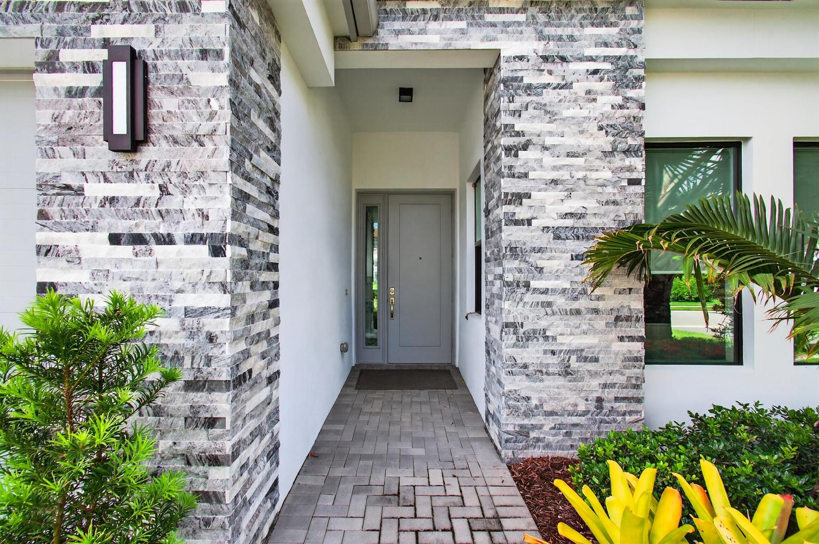 A front entryway features a gray door, stone-clad pillars, and a paved walkway — 17222 Blue Bayou Drive, Boca Raton FL 33496, BOCA RATON, FL