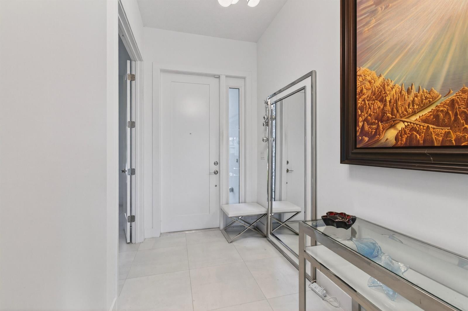 A bright entryway features white tile floors, a glass console table, and a large floor mirror — 17222 Blue Bayou Drive, Boca Raton FL 33496, BOCA RATON, FL