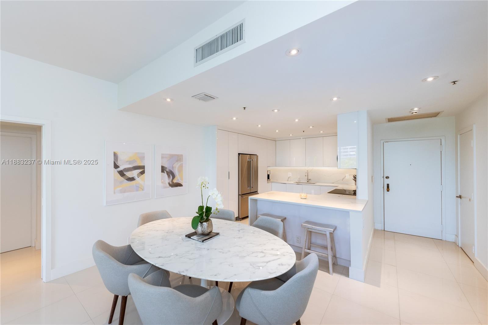 A modern kitchen and dining area feature a marble oval table and white cabinetry — 251 Crandon Blvd # 227, Key Biscayne FL 33149, KEY BISCAYNE, FL