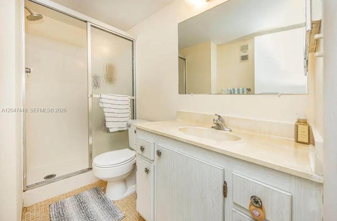 A bathroom features a shower stall, a white toilet, and a vanity with a mirror — 2615 NE 3rd Ct # 4030, Boynton Beach FL 33435, BOYNTON BEACH, FL