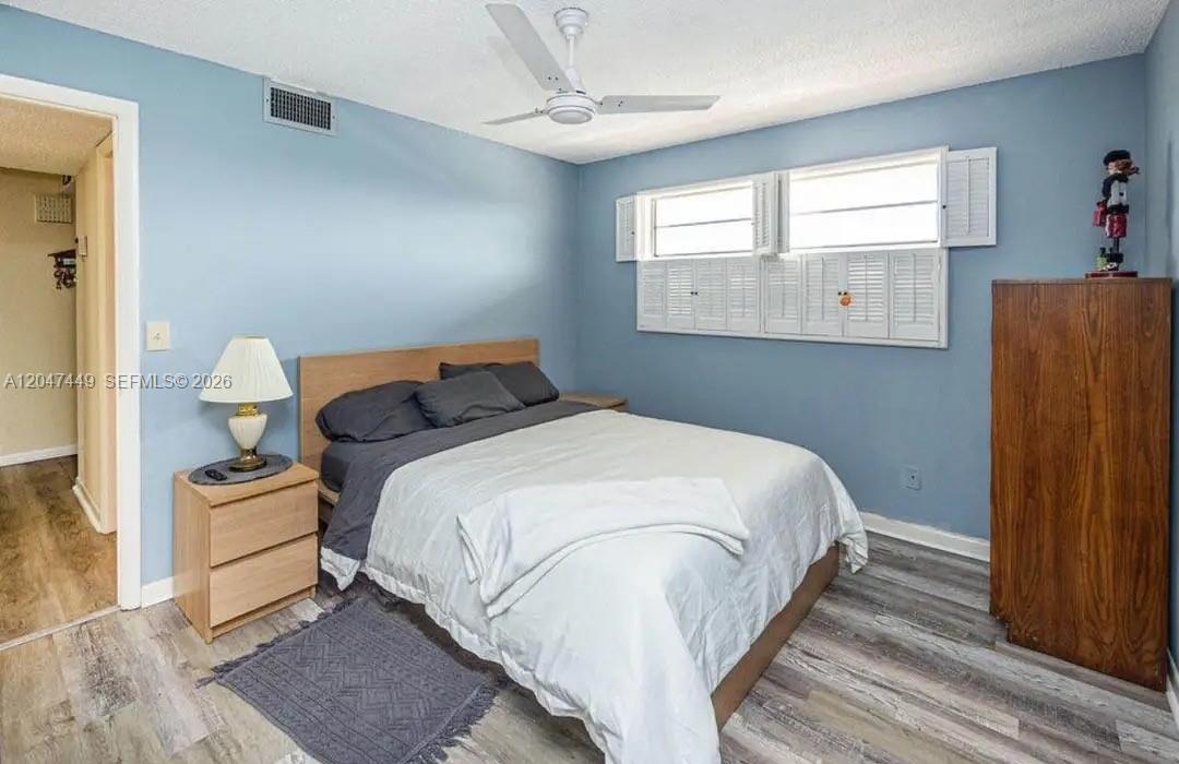 A bedroom with light blue walls, wood-look flooring, a bed, and a ceiling fan — 2615 NE 3rd Ct # 4030, Boynton Beach FL 33435, BOYNTON BEACH, FL