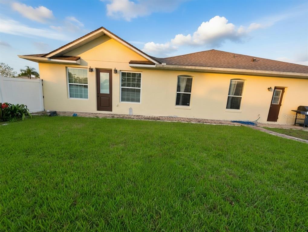 A single-story house with a tan stucco exterior, a two-car garage, and a front lawn — 2601 GOLD DUST CIRCLE, KISSIMMEE, FL