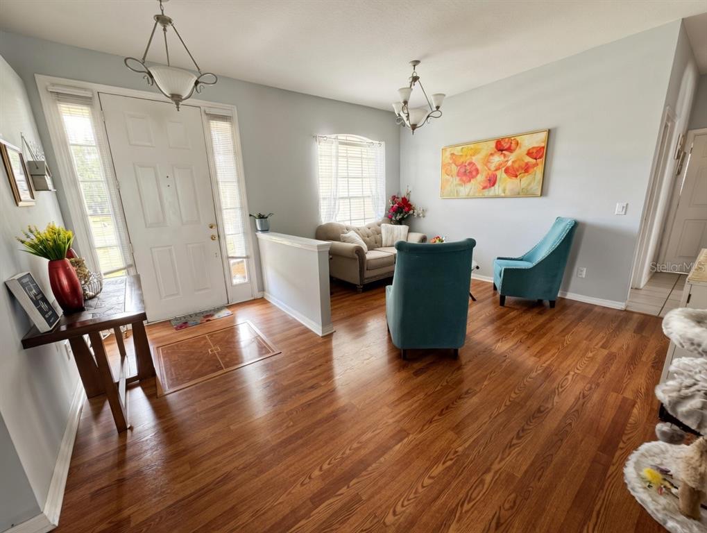 A living room features hardwood floors, a white front door, and two blue armchairs — 2601 GOLD DUST CIRCLE, KISSIMMEE, FL