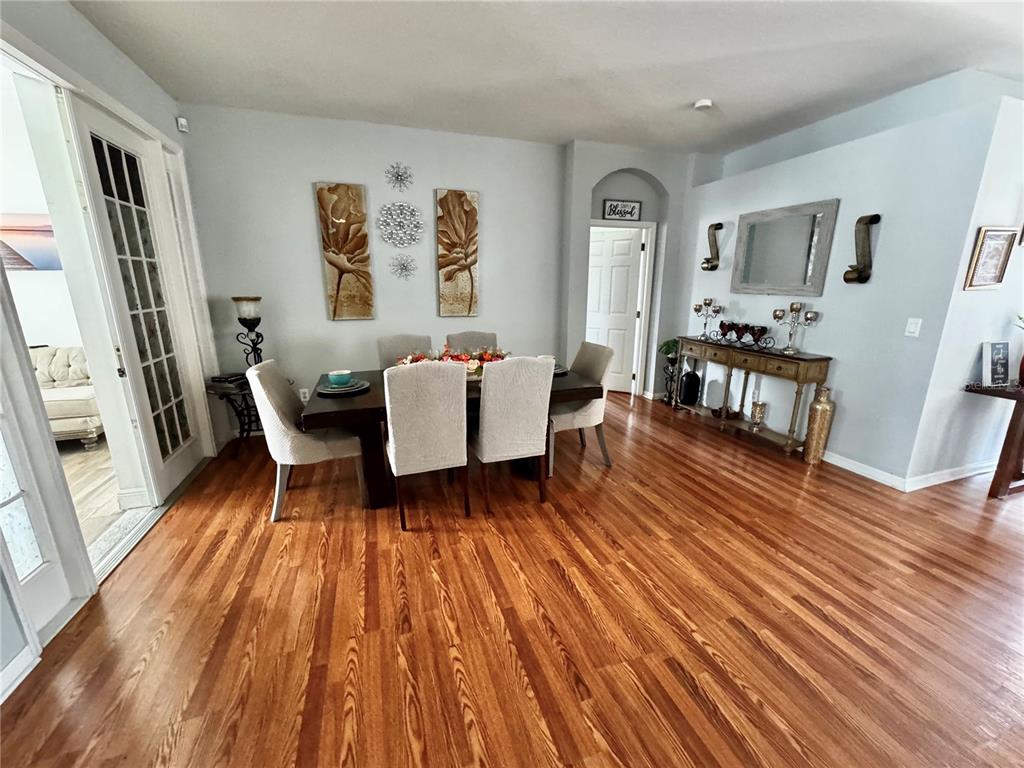 A dining room features a dark wood table, upholstered chairs, and hardwood flooring — 2601 GOLD DUST CIRCLE, KISSIMMEE, FL