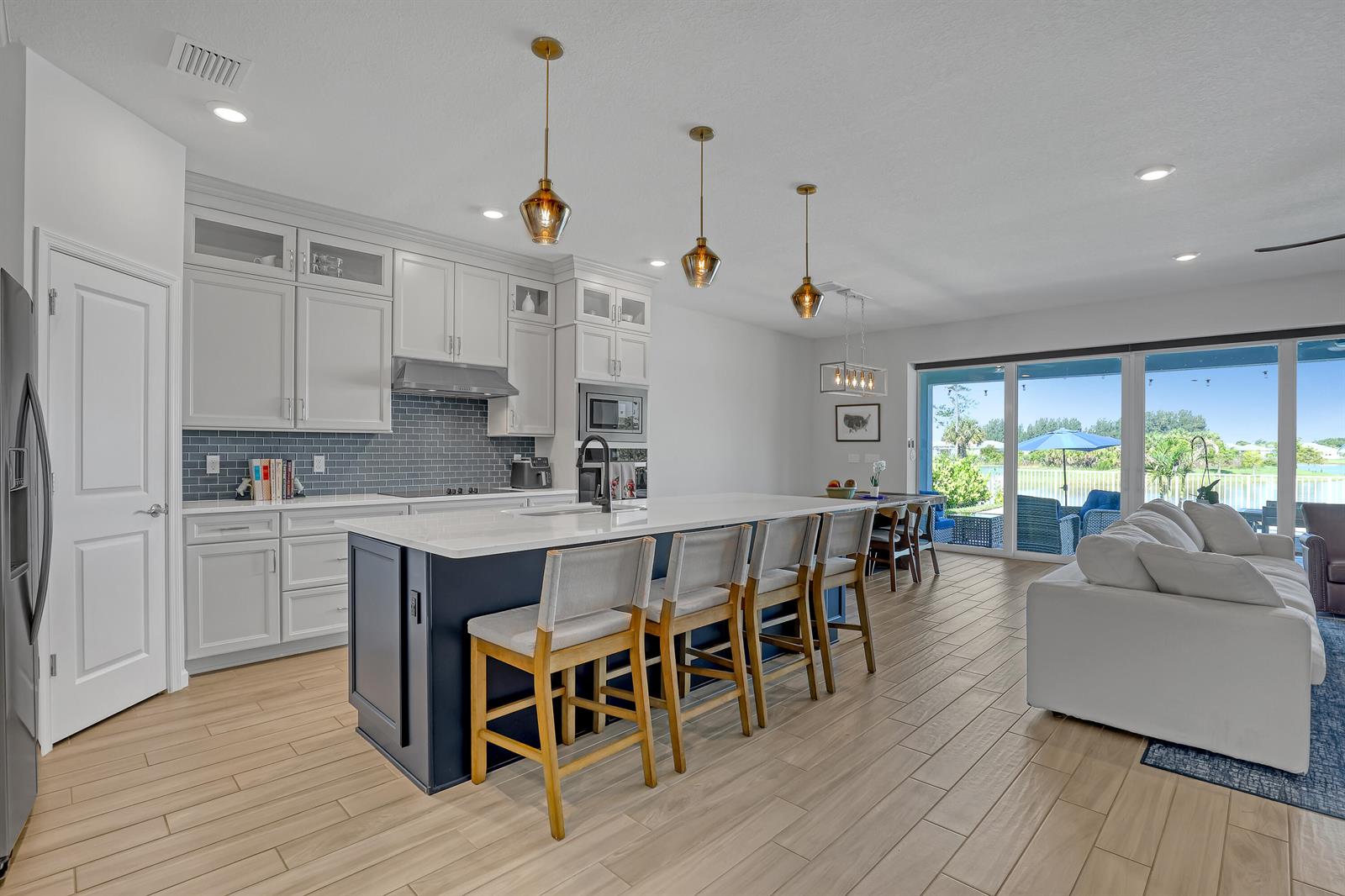 A kitchen with a dark blue island, white cabinets, and a view of a patio — 9774 SW Meridian Way, Stuart FL 34997, STUART, FL