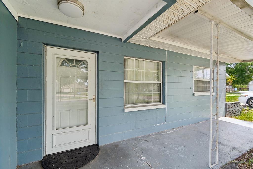 A blue concrete block house exterior features a white front door and a covered porch — 3521 74TH AVENUE N, PINELLAS PARK, FL