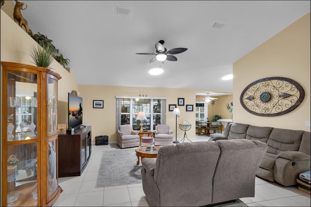 A living room with tile flooring, a grey sectional sofa, and a wooden display cabinet — 5193 SW 110TH PLACE, OCALA, FL