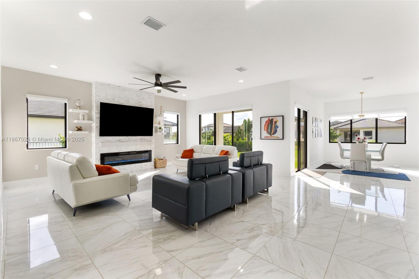 A bright living room features white marble floors, a stone fireplace, and modern furniture — 4948 Gambero Way, Ave Maria FL 34142, AVE MARIA, FL