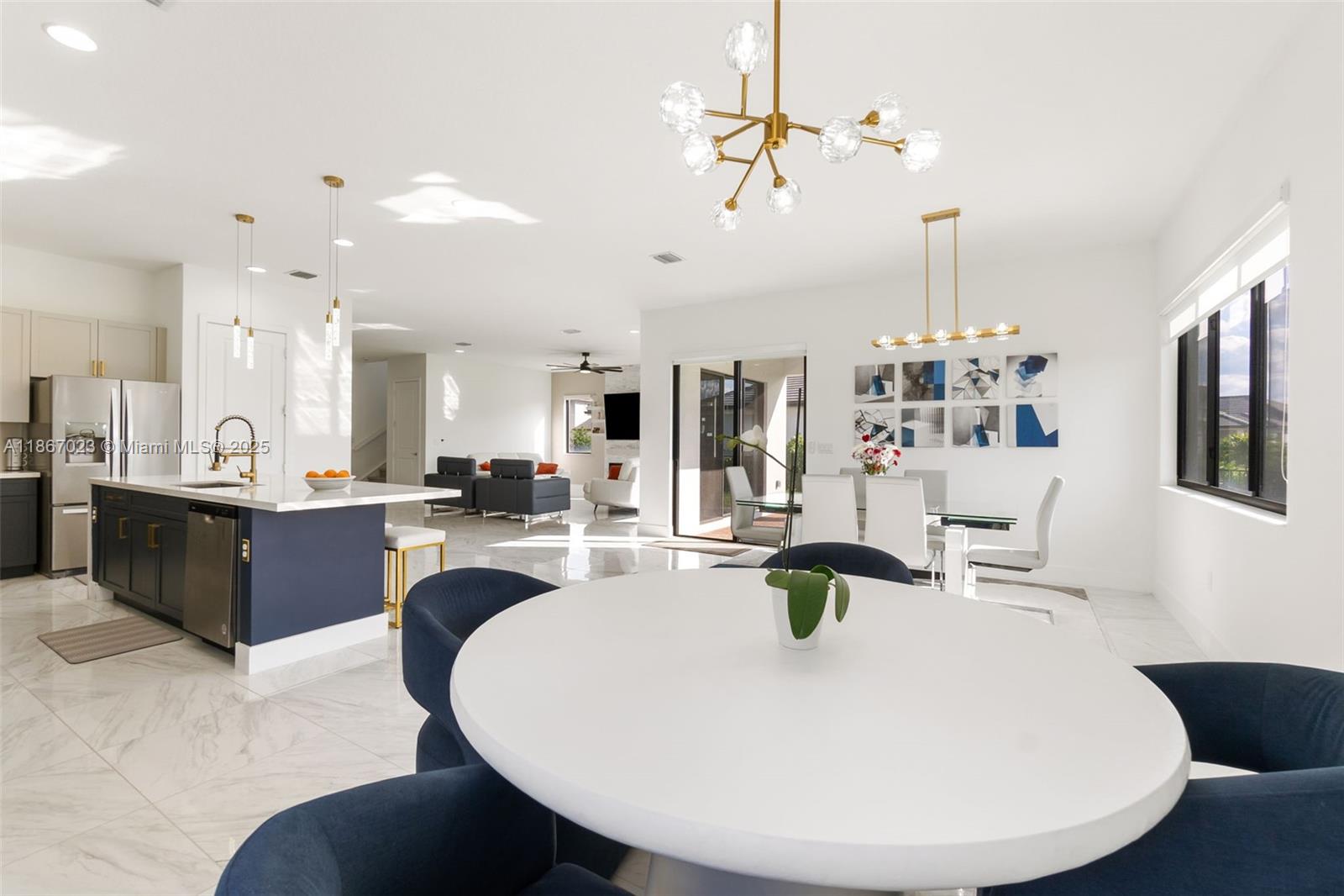 An open-concept kitchen, dining area, and living room feature white marble floors and modern lighting — 4948 Gambero Way, Ave Maria FL 34142, AVE MARIA, FL