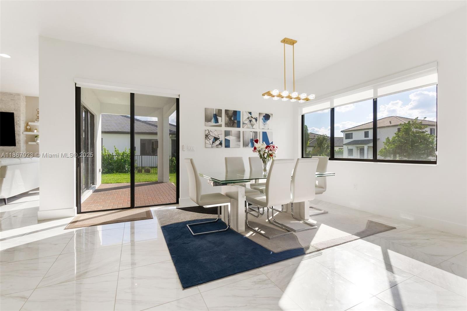 A dining room features a glass-topped table, white chairs, a modern chandelier, and tile flooring — 4948 Gambero Way, Ave Maria FL 34142, AVE MARIA, FL