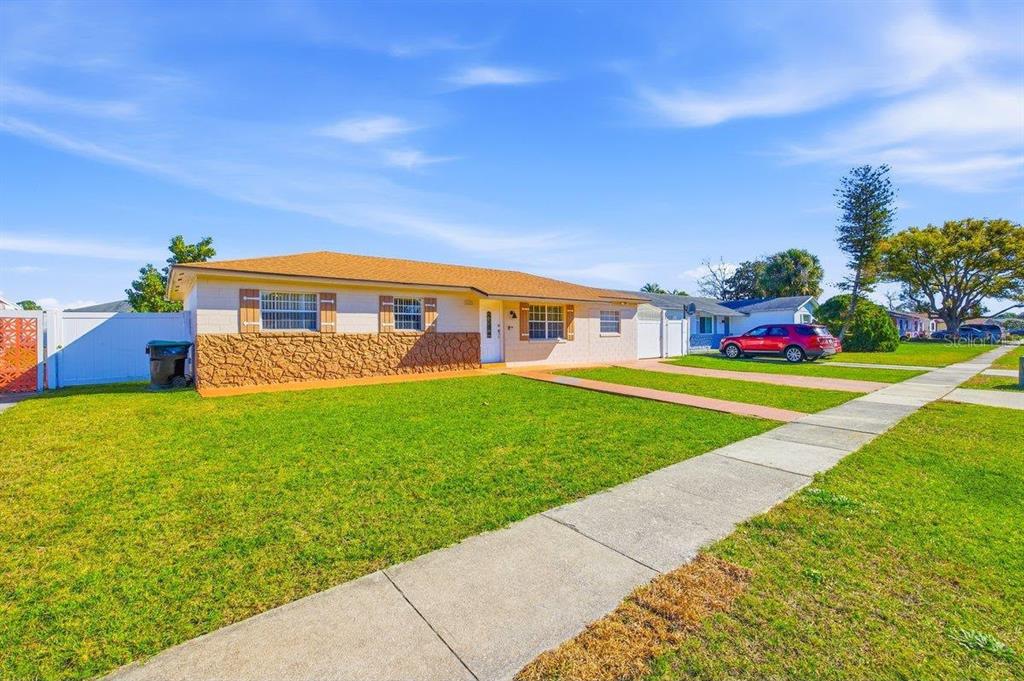 A single-story house with a tan exterior, stone accents, and a large front lawn — 5681 TULIP AVENUE, ORLANDO, FL
