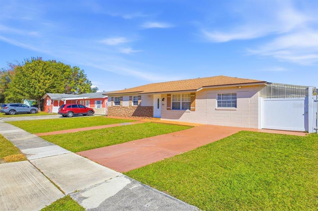 A single-story house with a tan exterior, a red driveway, and a white gate — 5681 TULIP AVENUE, ORLANDO, FL