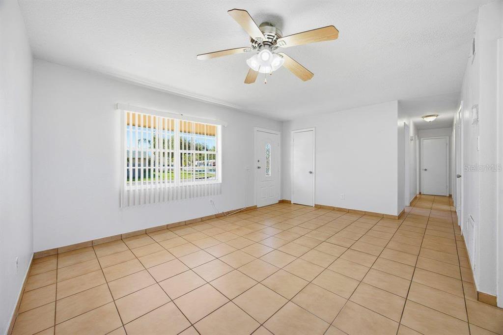 An empty room with light-colored tile flooring, a ceiling fan, and a window with blinds — 5681 TULIP AVENUE, ORLANDO, FL
