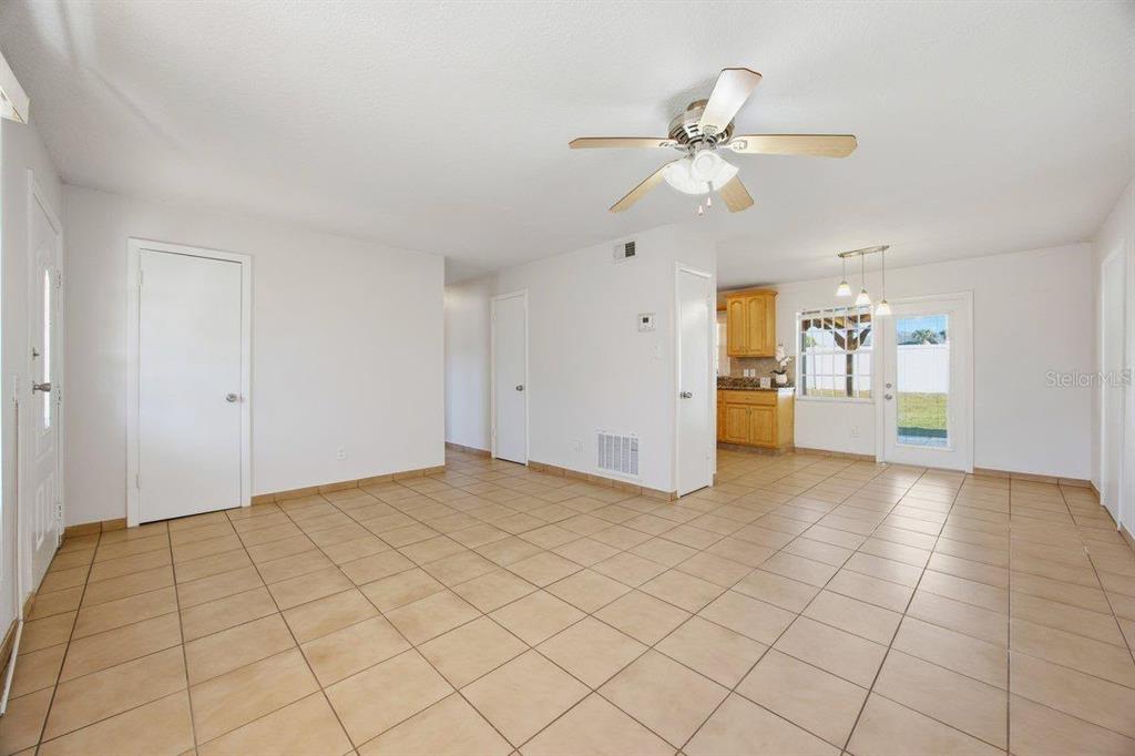 An open-concept living and dining area features light-colored tile flooring and a ceiling fan — 5681 TULIP AVENUE, ORLANDO, FL