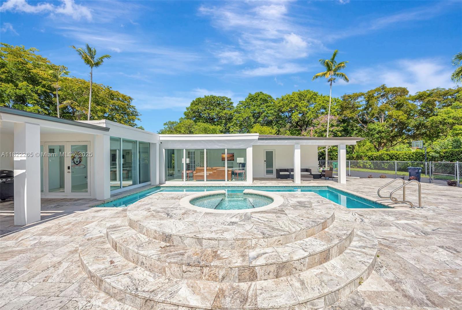 A modern white house features a tiered stone hot tub beside a swimming pool — 11230 SW 69th Ct, Pinecrest FL 33156, PINECREST, FL