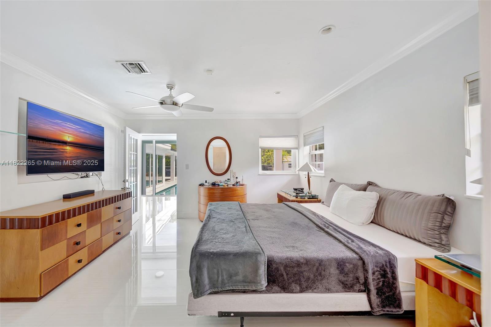 A bedroom features a bed, a dresser with a television, and a door to a pool — 11230 SW 69th Ct, Pinecrest FL 33156, PINECREST, FL
