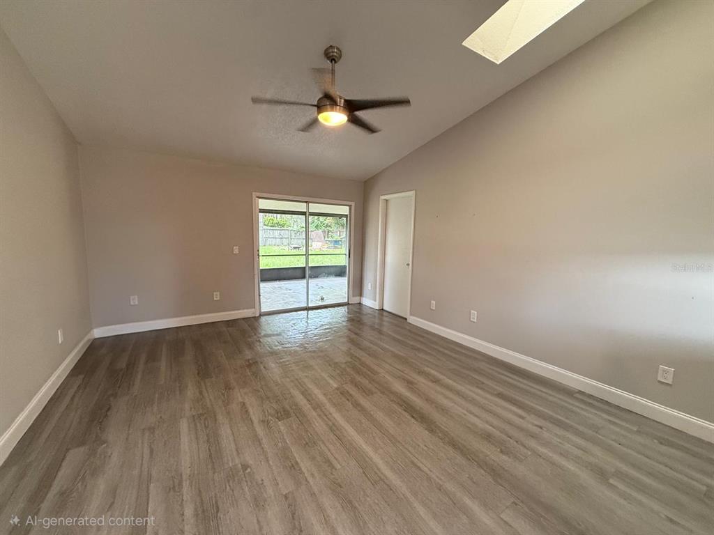 An empty room with light gray wood-look flooring, a ceiling fan, and sliding glass doors — 3010 GALAXY STREET, DELTONA, FL
