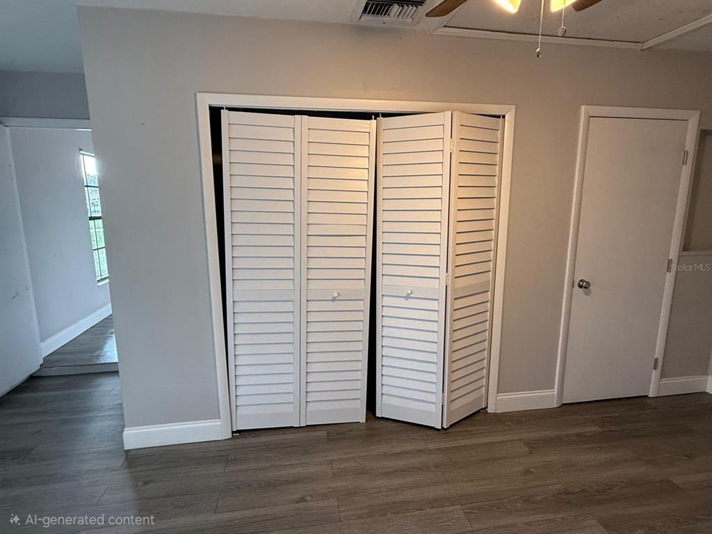 A room features gray walls, wood-look flooring, a louvered bifold closet, and a white door — 3010 GALAXY STREET, DELTONA, FL