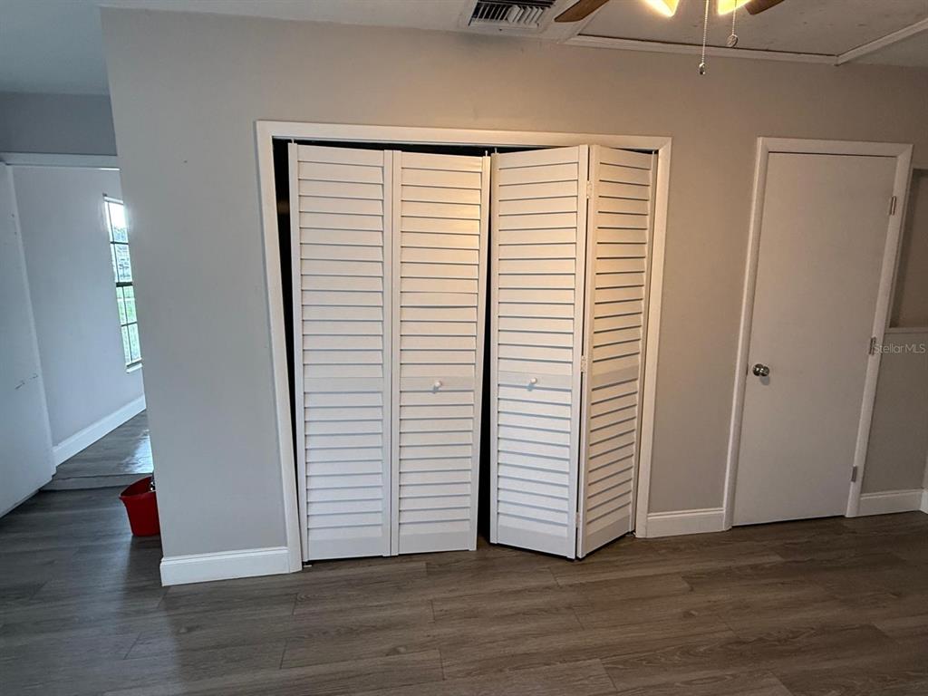 A room with gray walls, wood-look flooring, a louvered closet door, and a standard door — 3010 GALAXY STREET, DELTONA, FL