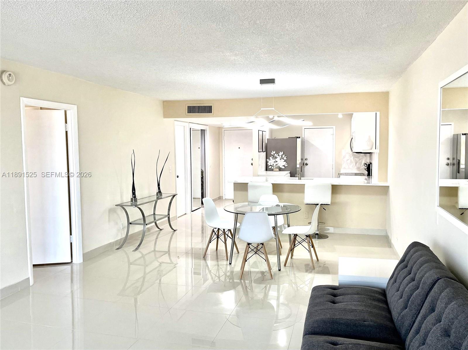 A bright, open-concept living and dining area features white tile floors and modern furniture — 800 SE 20th Ave # 1109, Deerfield Beach FL 33441, DEERFIELD BEACH, FL