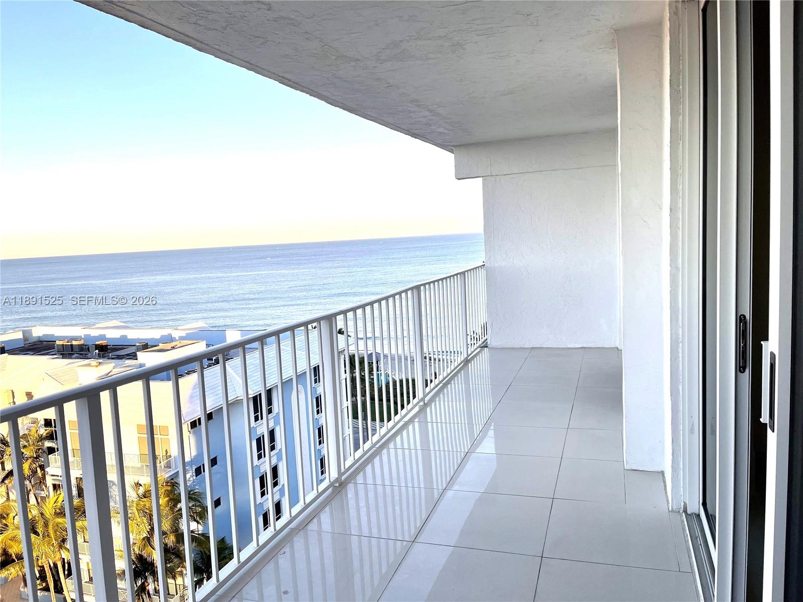 A tiled balcony with a white metal railing overlooks the ocean and nearby buildings — 800 SE 20th Ave # 1109, Deerfield Beach FL 33441, DEERFIELD BEACH, FL