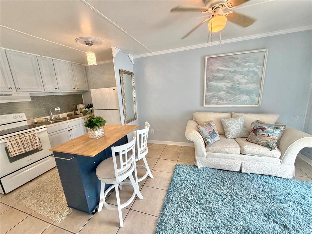 A kitchen with a blue island and stools sits adjacent to a living area — 10301 US HIGHWAY 27 UNIT 192, CLERMONT, FL
